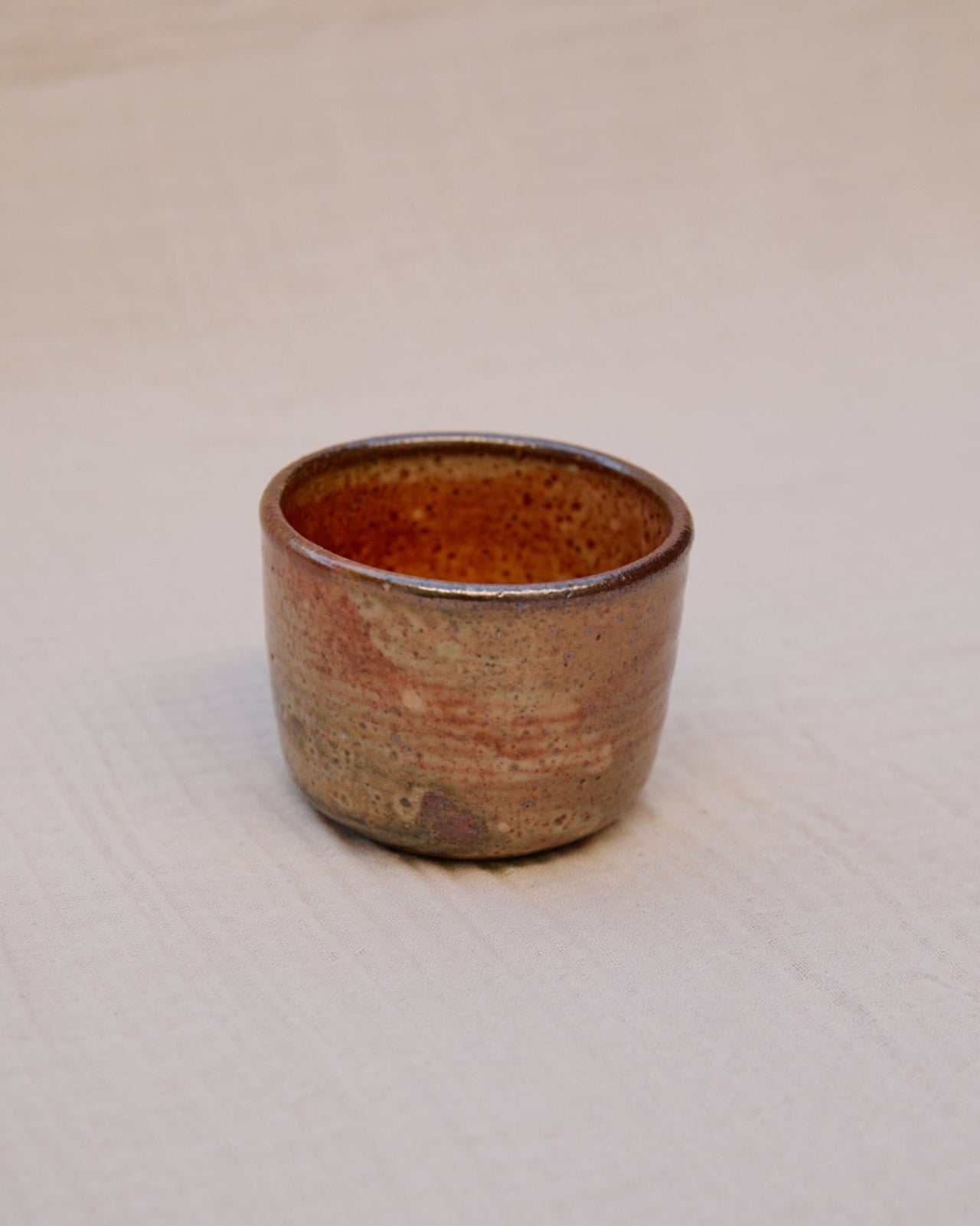 Small ceramic cup with a textured surface on a white background
