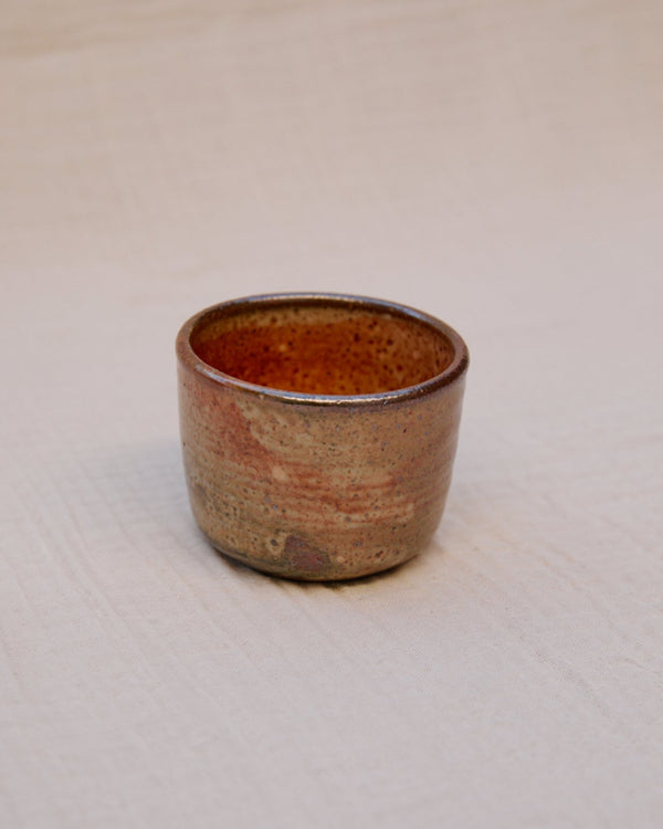 Small ceramic cup with a textured surface on a white background