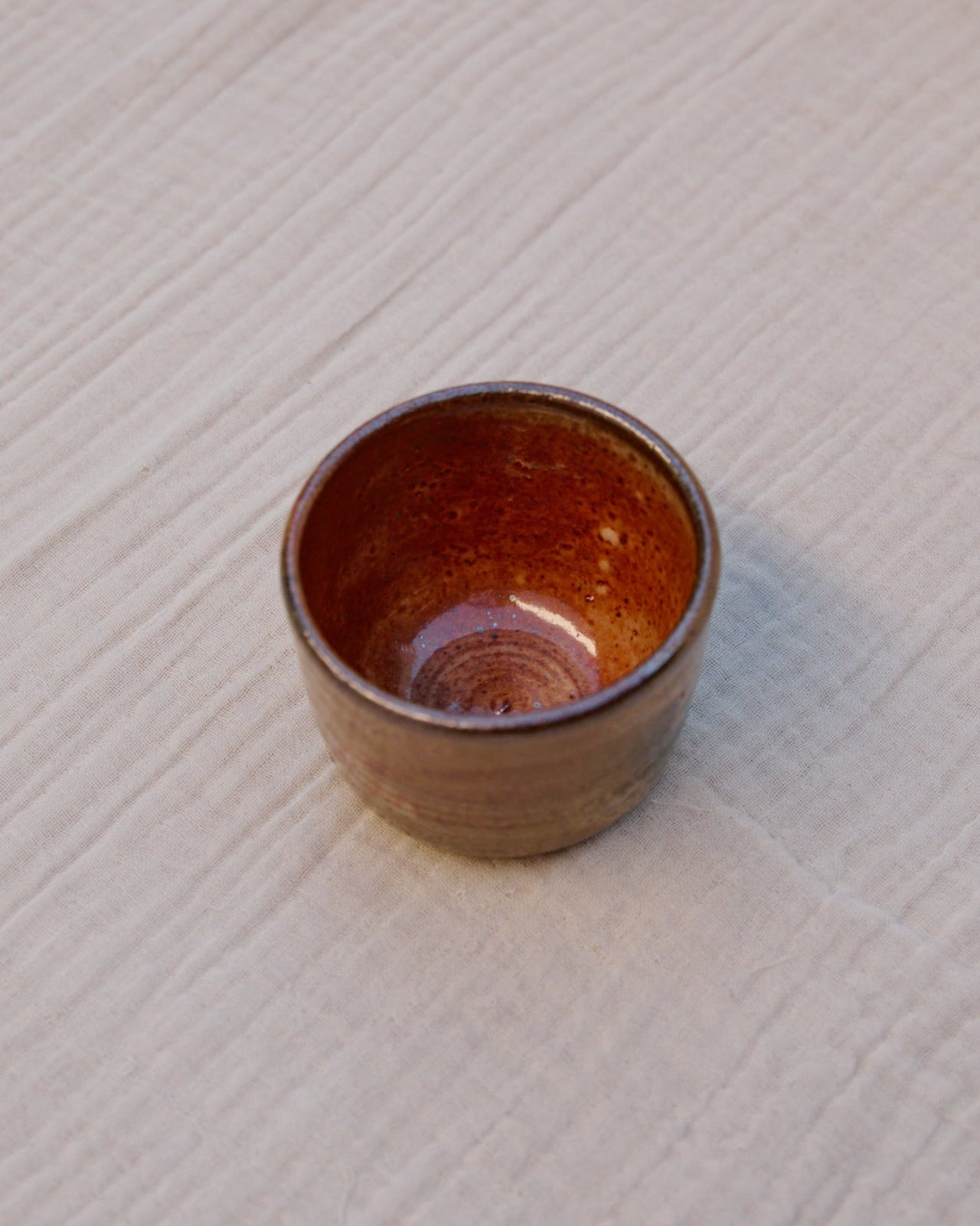 Brown ceramic cup on a textured white surface